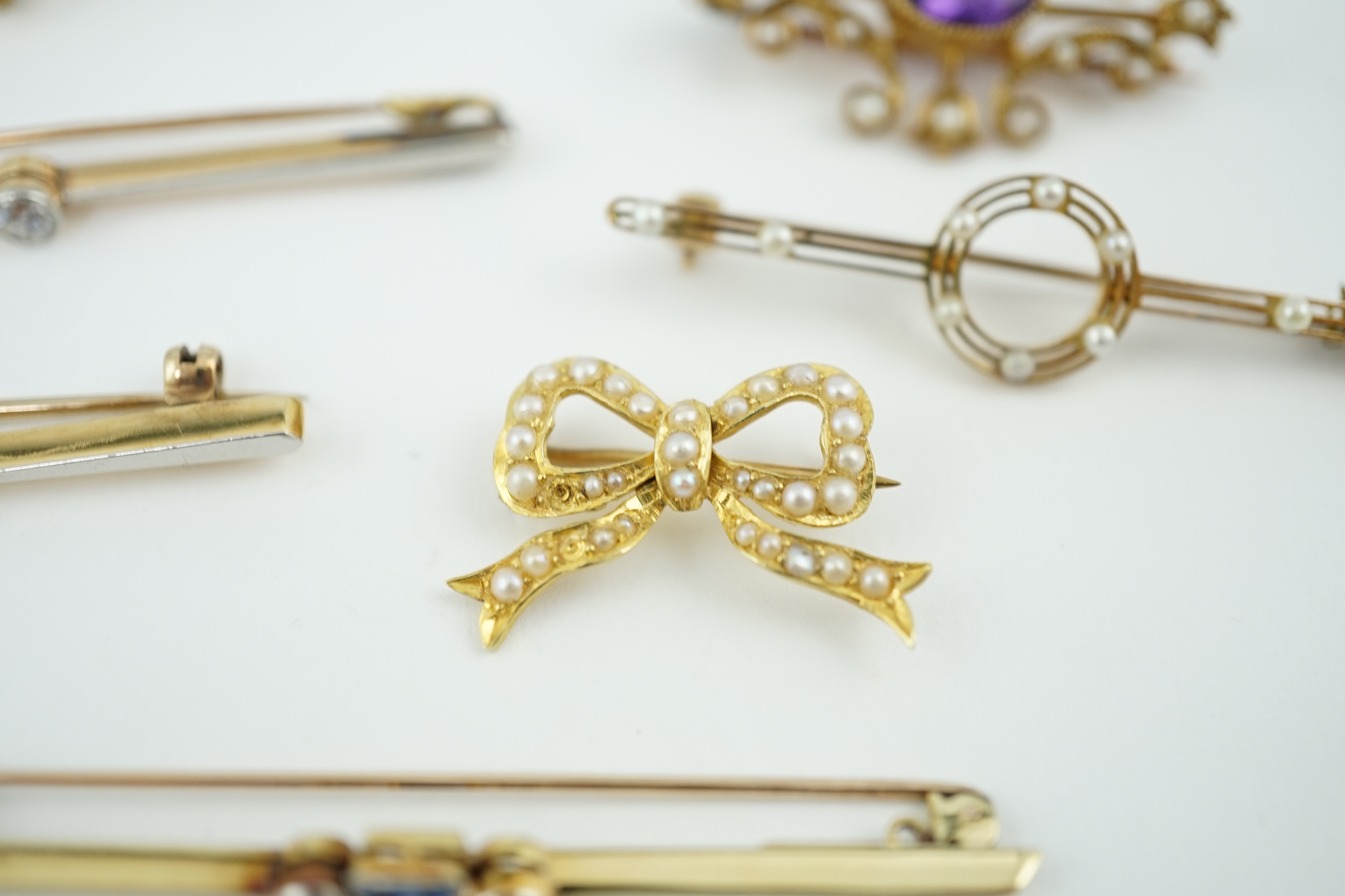 Five assorted Edwardian bar brooches, including a 15ct gold sapphire and diamond set three stone, a diamond and seed pearl, ruby? and seed pearl, a solitaire diamond set and a seed pearl and citrine bug brooch